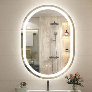 Ovalus apsviestas veidrodis vonios kambaryje su matomu dusu atspindyje, svelnus sviesos konturas ir dekoratyvios lentynos salia.