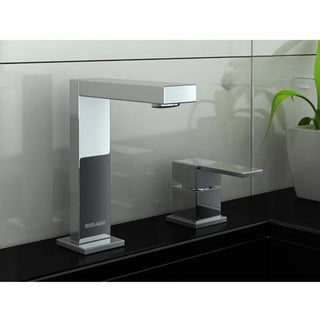 Dviejų skylių Kohlman Excelent praustuvo maišytuvas su kampuotu snapeliu ir atskira valdymo rankenėle, sumontuotas ant juodo paviršiaus.