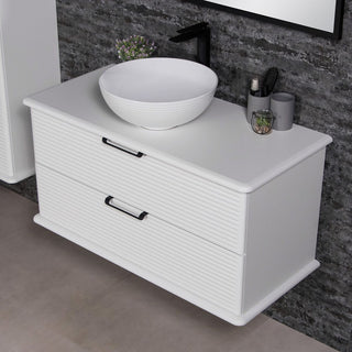 Baltos spalvos Libra spintele su dubens formos kriaukle ir juodais aksesuarais ant stalvirsio.