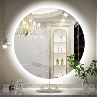 Didelis apšviestas apskritas veidrodis virš balto stalviršio su auksiniais maišytuvais ir elegantišku šviestuvu.